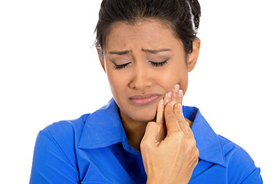 Woman in blue shirt with hand to face, expressing concern or worry.