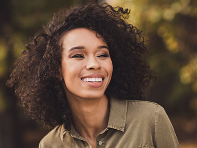 A woman with curly hair, smiling and looking towards the camera.