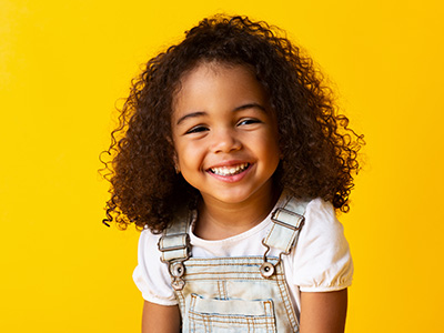 The image features a young child with curly hair, smiling at the camera.