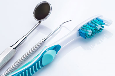 A dental tool set, including a toothbrush and dental instruments, on a white background.